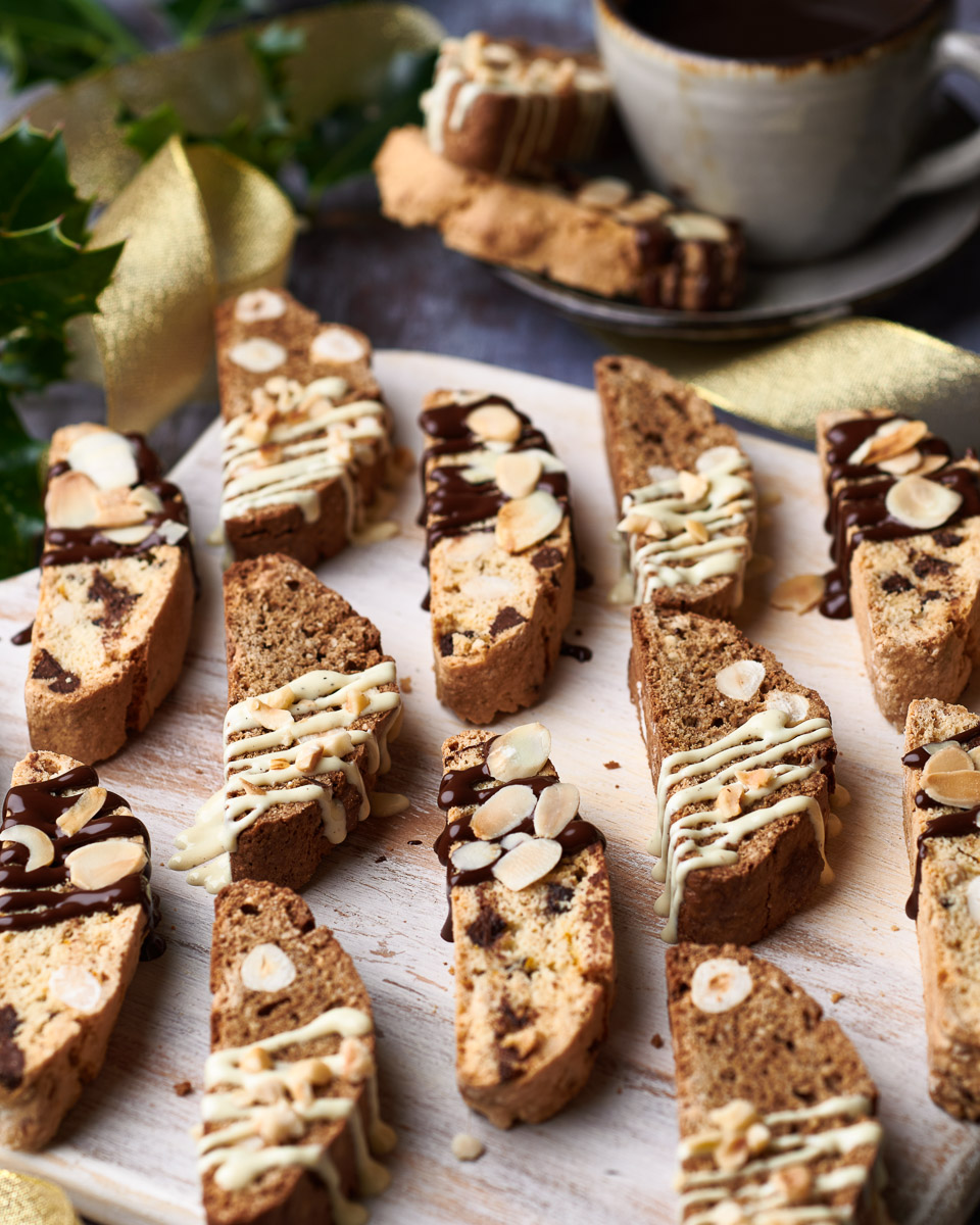 professional food photography of biscotti spread on a board with milk chocolate and white chocolate drizzle
