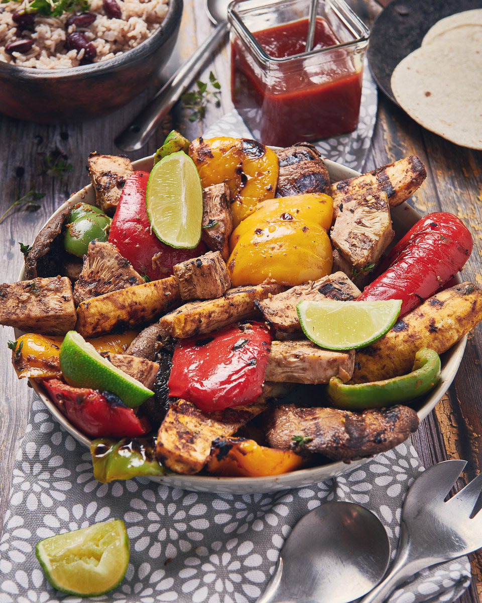 a frame filling shot of chargrilled Caribbean jackfruit with peppers and lime wedges in a lifestyle environment. shot by professional food photographer for coeliac uk in connection with delicious by design
