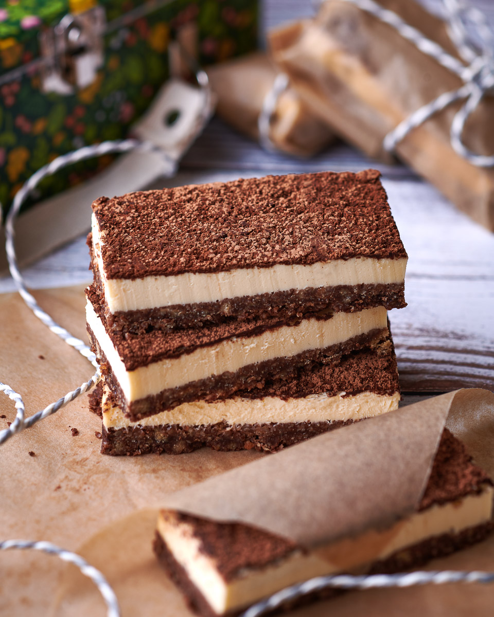 professional food photography of a stack of cheesecake slices, shot from the side with greaseproof paper and string in image