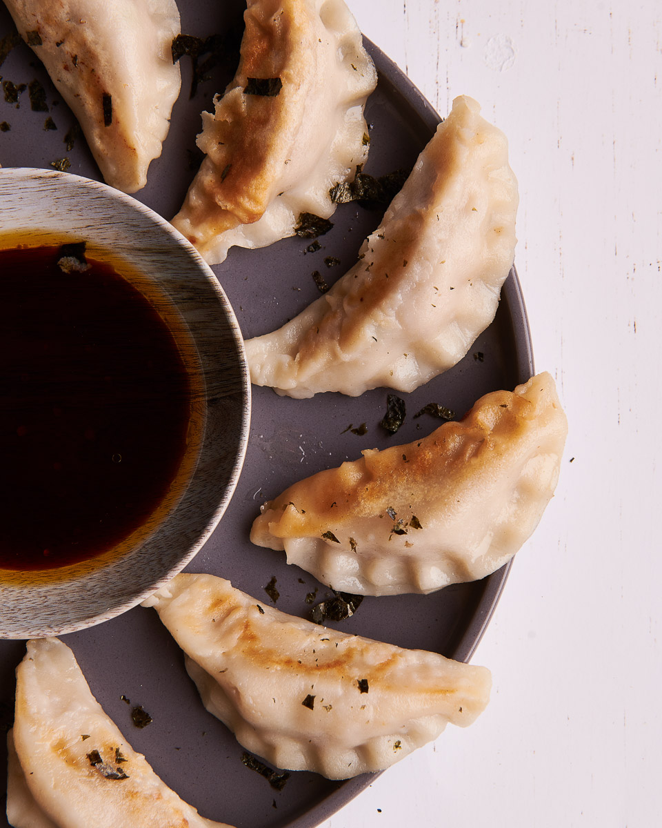 close up food photography of gyoza dumplings with a dip bowl
