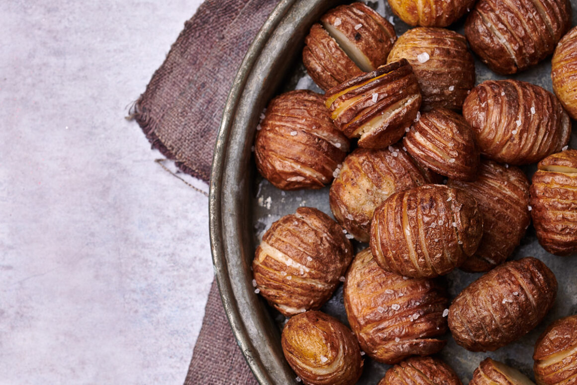 hassleback potatoes, close up in a tray, sprinkled with salt and shot top down