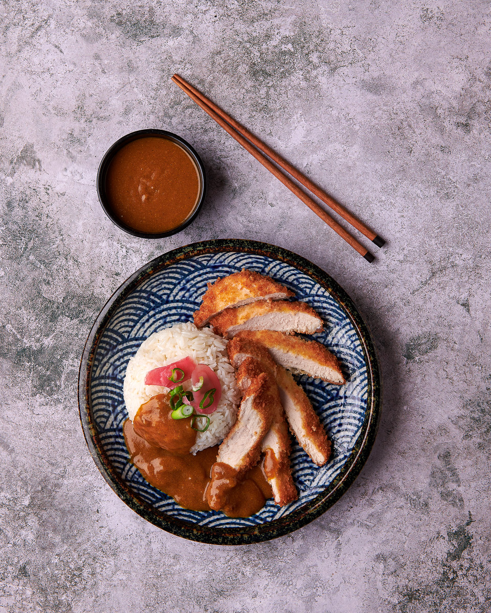 top down photo of chicken Katsu curry with side pot of sauce and chopsticks