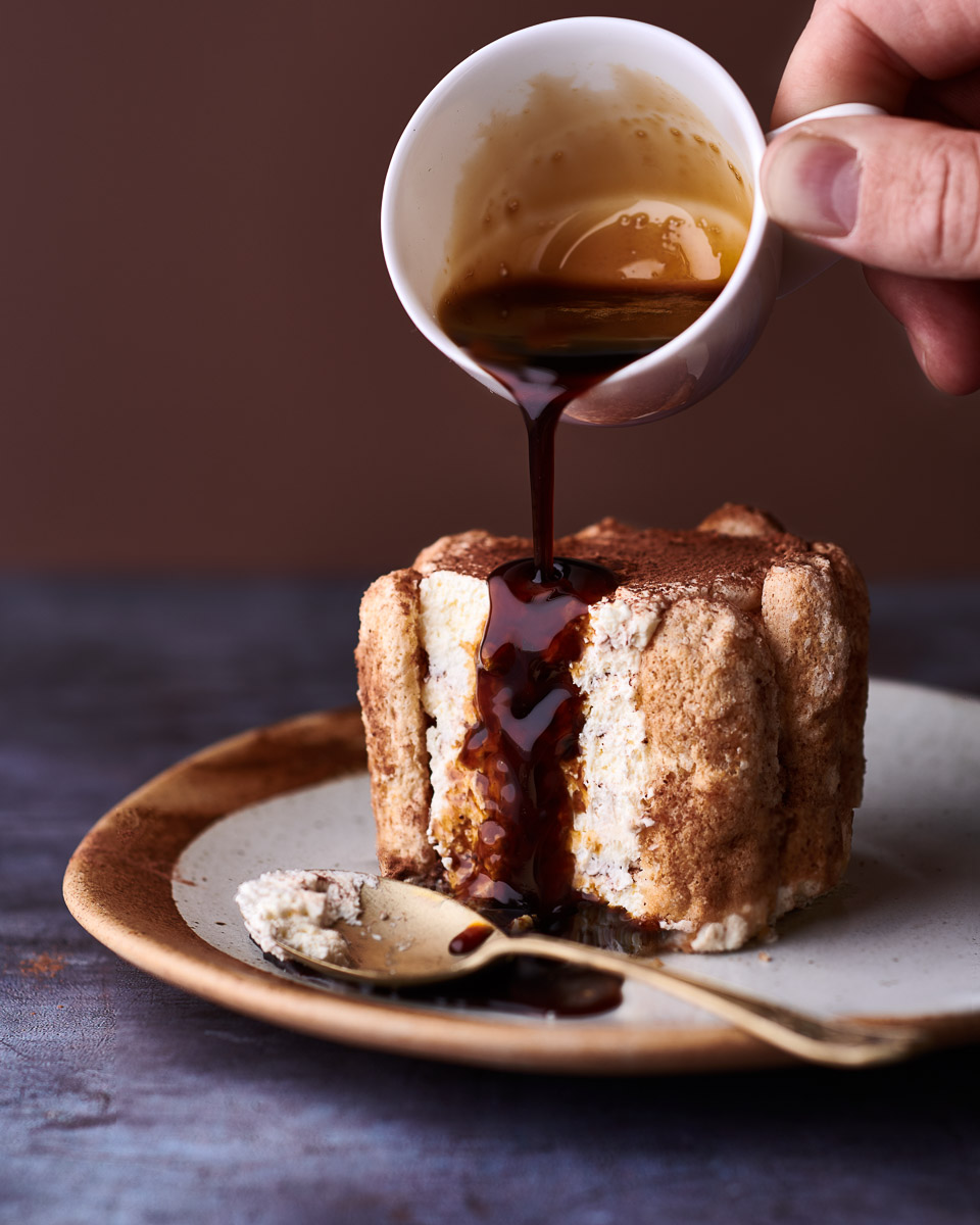 professional close up food photography of a single serving of tiramisu with coffee liqueur being poured over. shot for coeliac UK