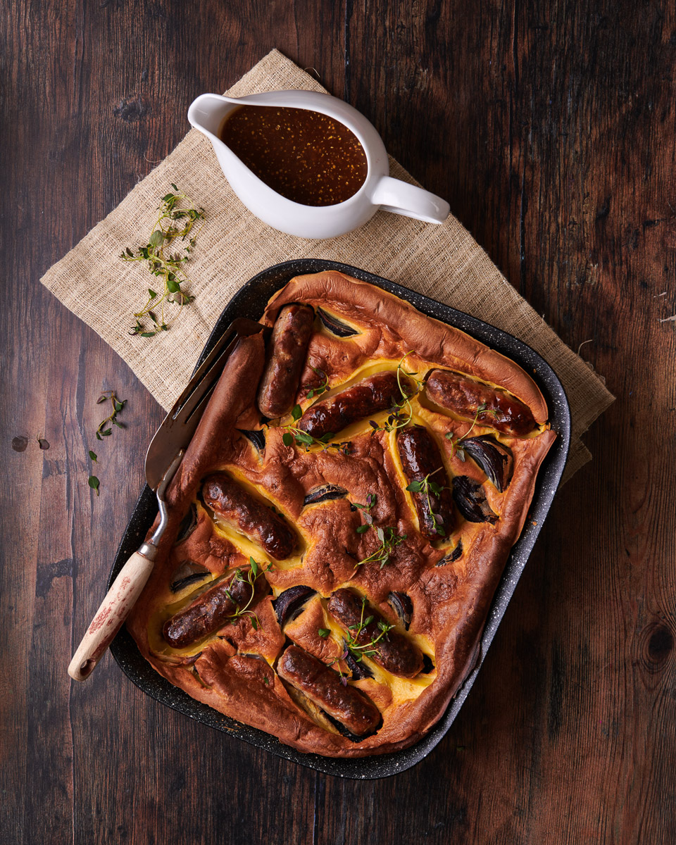 toad in the hole with gravy in jug, top down image